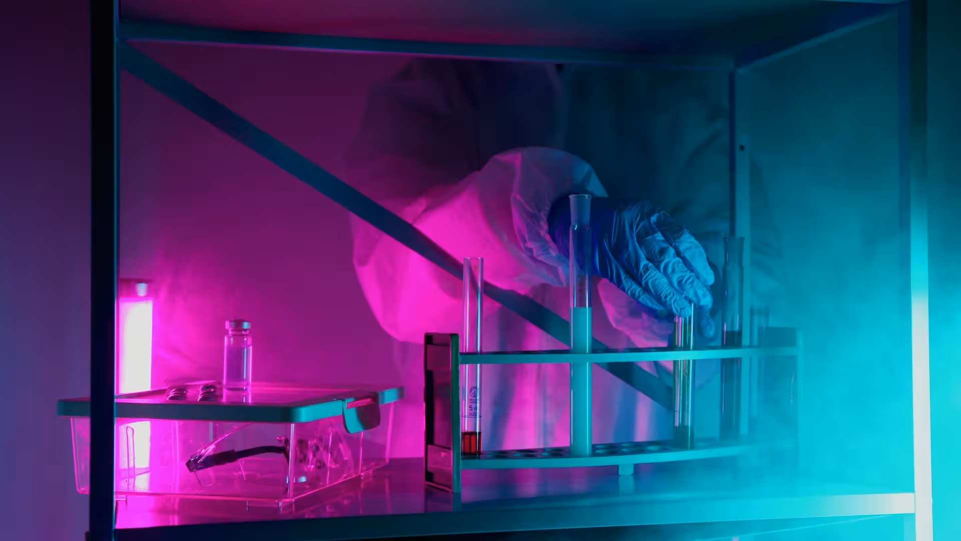 Laboratory worker handling test tubes under magenta and cyan light